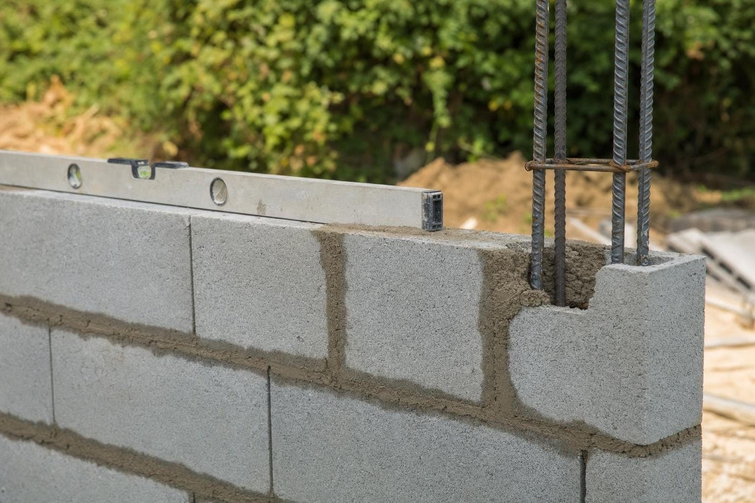 Angle de mur en blocs béton avec chaînage vertical ferraillé et joints de mortier frais