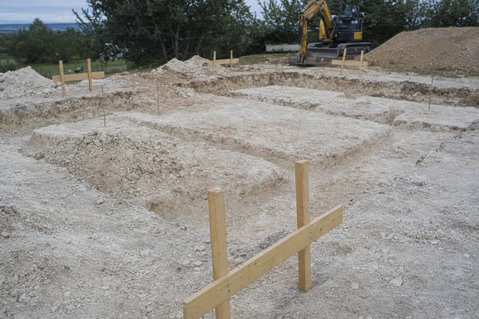 Chaises d'implantation et cordeaux tendus au-dessus de fouilles creusées dans un sol crayeux