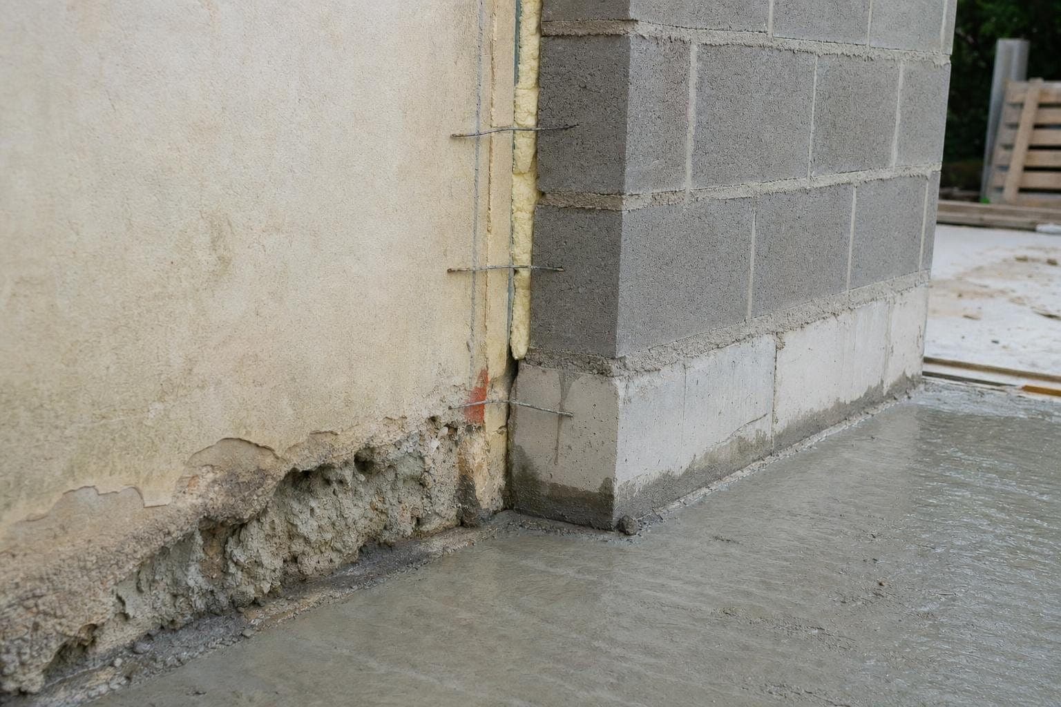 Jonction entre le mur d'une maison existante et les murs neufs en blocs béton d'une extension
