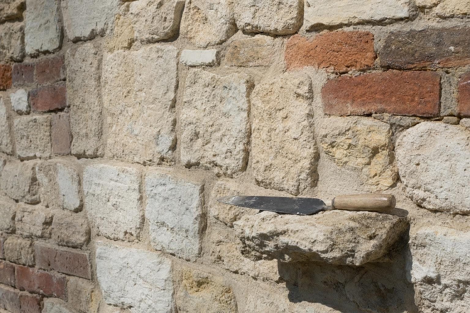 Vieux mur en pierre de craie et brique avec pierres remplacées et joints refaits à la chaux