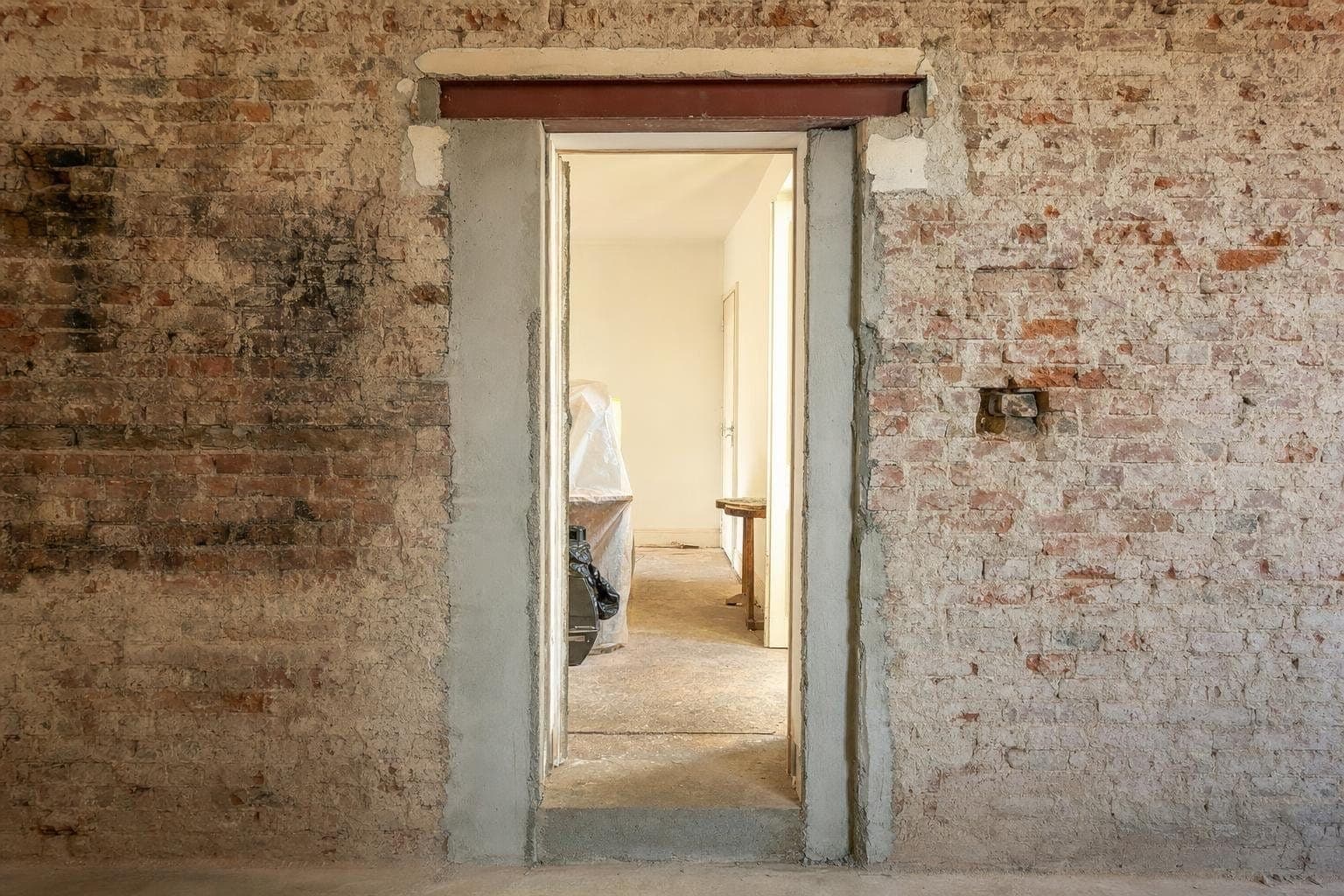Passage de porte élargi dans un mur de brique ancienne, tableaux repris au mortier